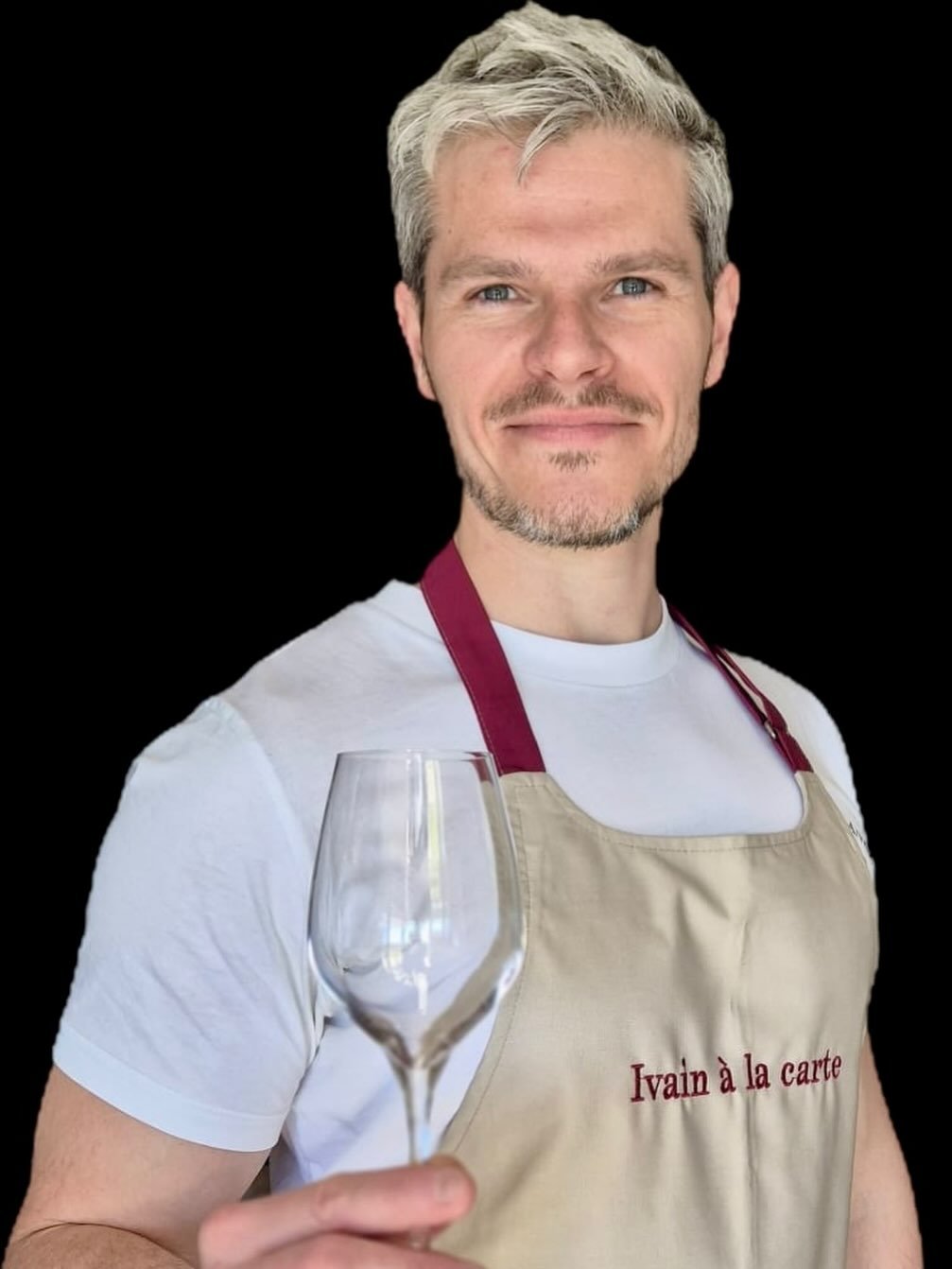 Jérôme Ivain, en tablier Ivain à la carte, un verre à la main